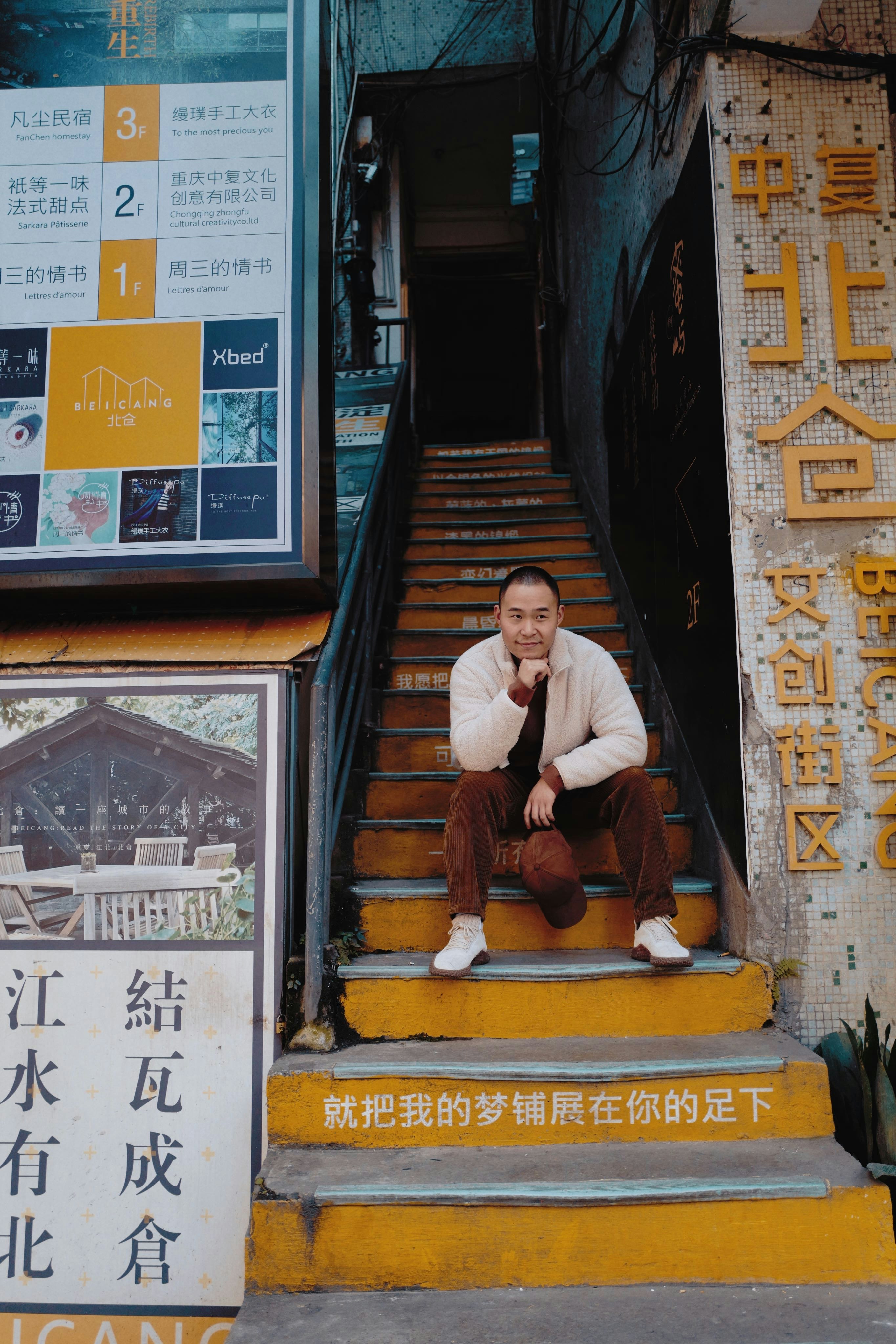 man sitting on stairs and looking at the camera during day